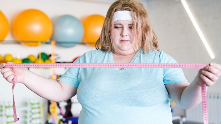 Mujer obesa preocupada con cinta métrica