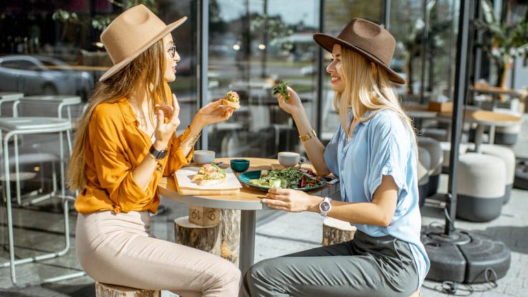 Mujeres con sombrero comiendo alimentos saludables al aire libre