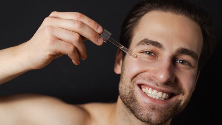 Hombre joven aplicándose serum facial