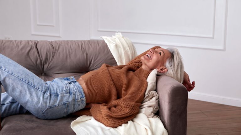 Mujer de mediana edad riendo tumbada en un sofá